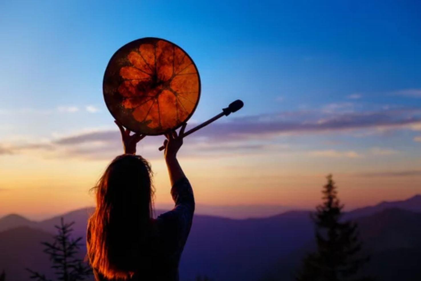 Sarah Ellwood, circle facilitator, standing on a mountain top at sunrise